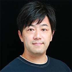 Portrait of a man with short black hair in a dark top, black background