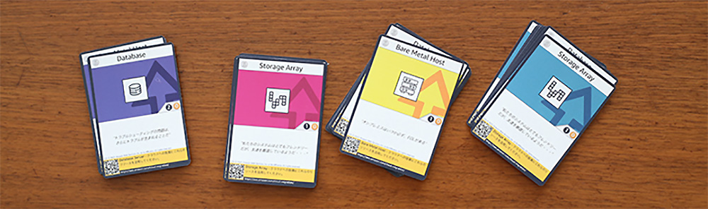 A set of Japanese builder cards displayed on a wooden surface, featuring categories such as Database, Storage Array, and Bare Metal Host with illustrated icons and Japanese text.