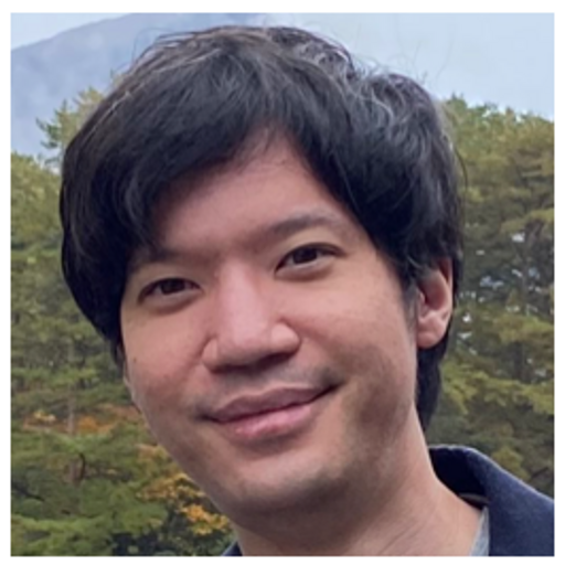 Outdoor portrait of a person with short black hair standing in front of trees.