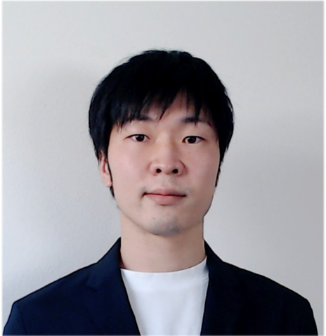Professional portrait of a man with short black hair wearing a dark blazer and white shirt, facing forward against a plain background.