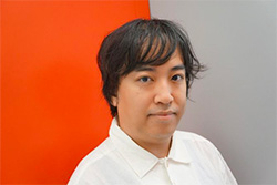 Portrait of a person with dark hair wearing a white shirt, standing in front of a split red and gray background.