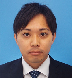 Formal portrait of a man in a suit and tie against a blue background.