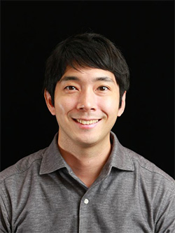 Portrait of a man in a grey shirt against a black background