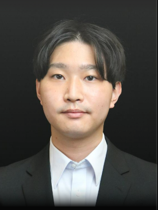 A professional portrait photograph of a man wearing a black suit and white shirt, against a dark background.