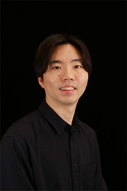 A portrait of Ishibashi Naoki wearing a black shirt, set against a black background.