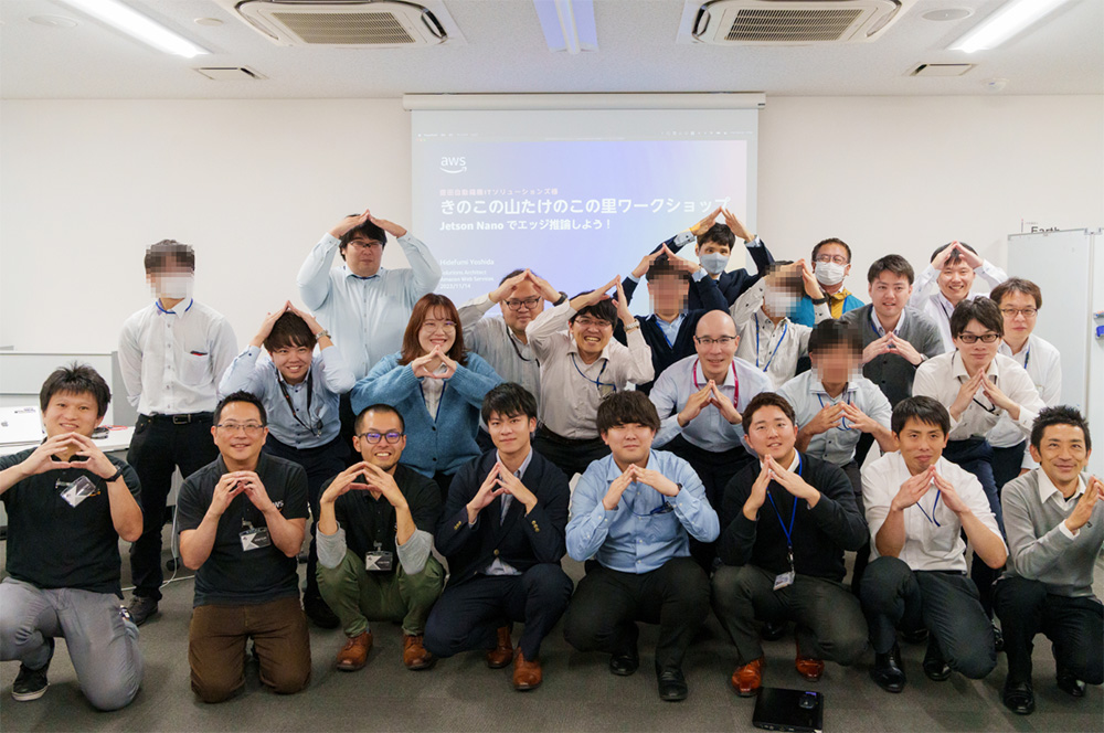 Group photo of participants at an AWS engineer workshop in Japan in 2024. The group is posing together in a classroom setting, with a presentation screen visible in the background.