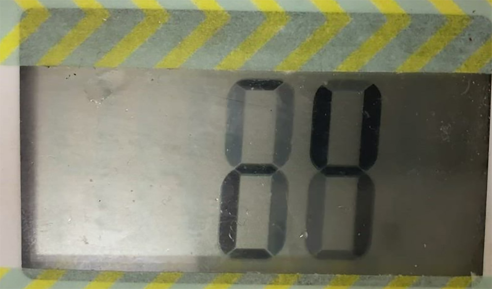 Close-up image of a digital LCD display showing the number 88, bordered by a pattern of yellow and gray diagonal stripes.
