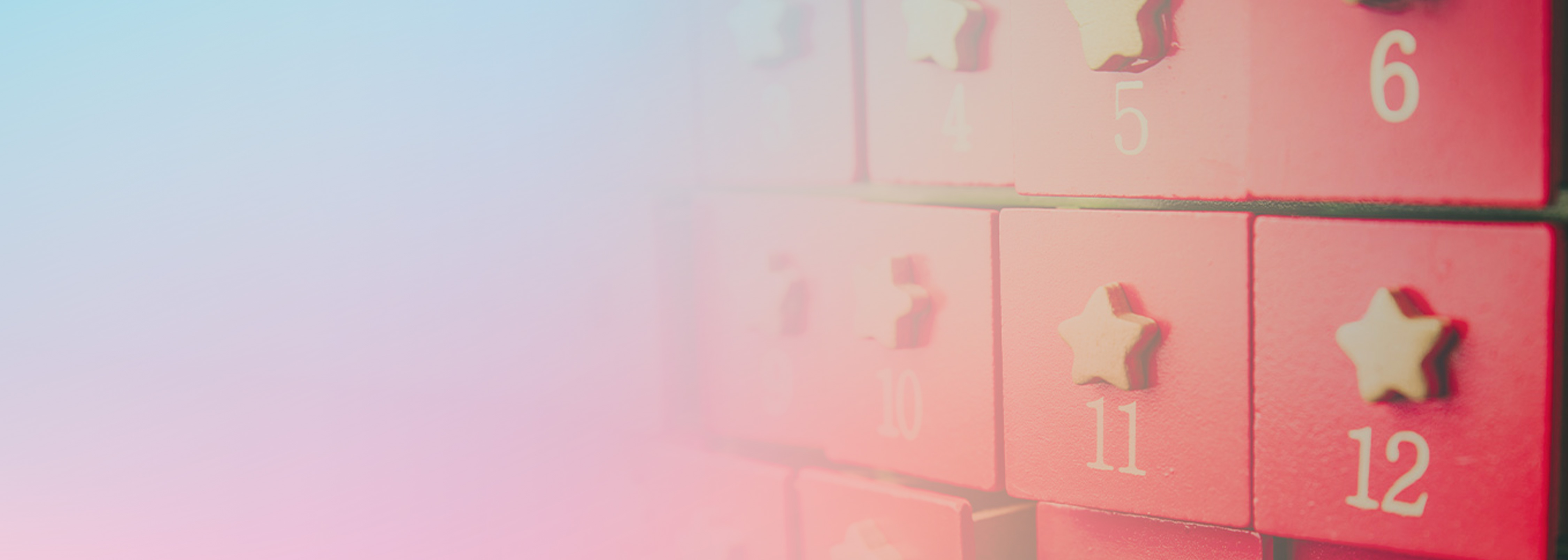 Close-up of an advent calendar featuring red drawers with white numbers and small star-shaped handles, partially blurred with a pastel gradient overlay.