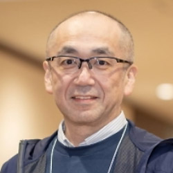 Portrait of a man wearing glasses, photographed indoors, with a blurred background.