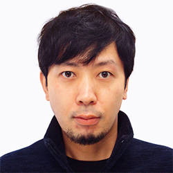 Portrait photo of a man with black hair and a trimmed beard, wearing a dark top, facing forward against a plain background.