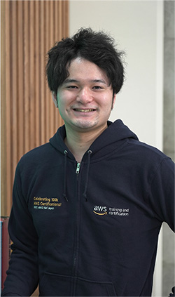 AWSトレーニングと認定のパーカーを着た男性（杉山氏）が笑顔で写っている写真。
