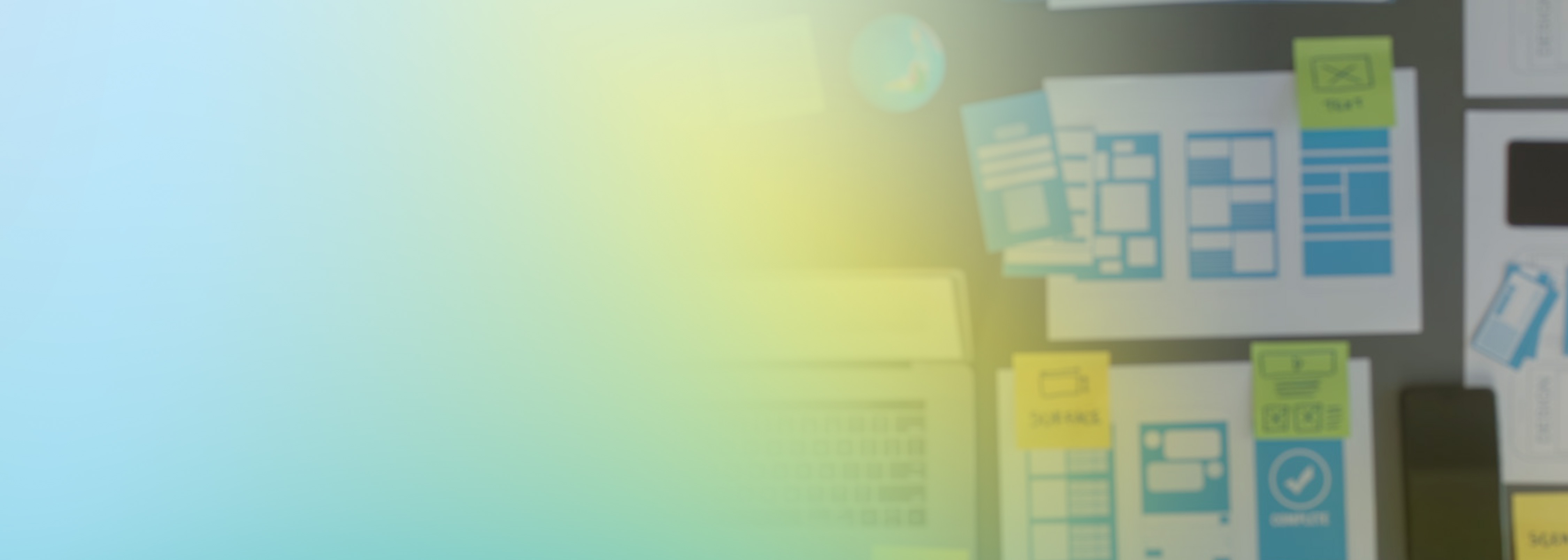 A blurred image showing application wireframes, sticky notes, and planning materials on a desk, representing distributed load testing and user interface design processes.