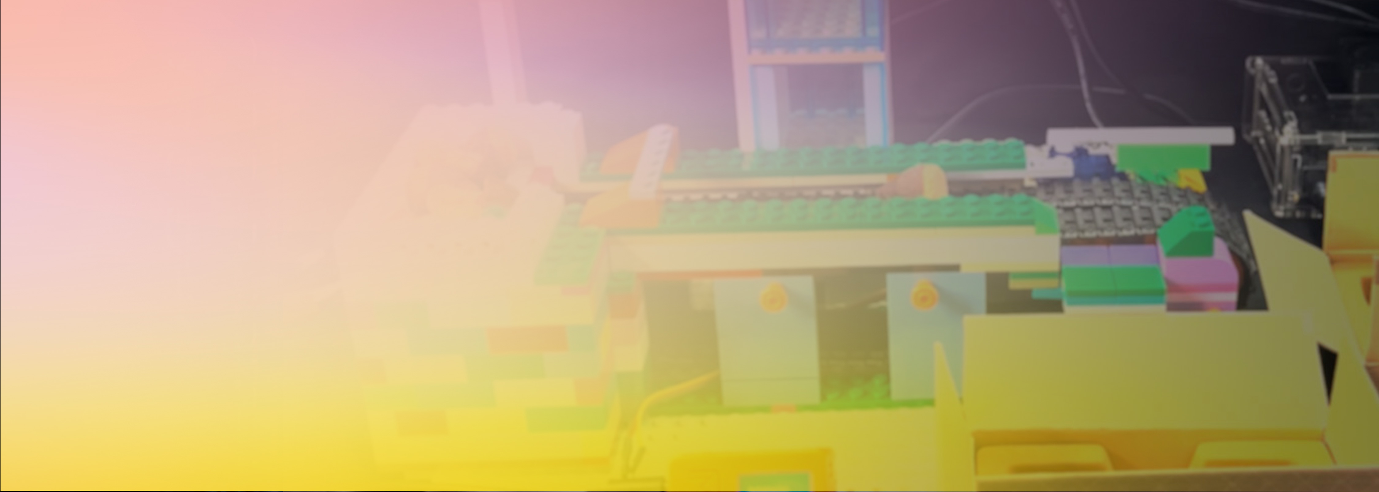 A partially blurred image of a model created from colorful interlocking blocks, likely resembling a Kinoko Takenoko theme, with soft pink and yellow gradient overlay.