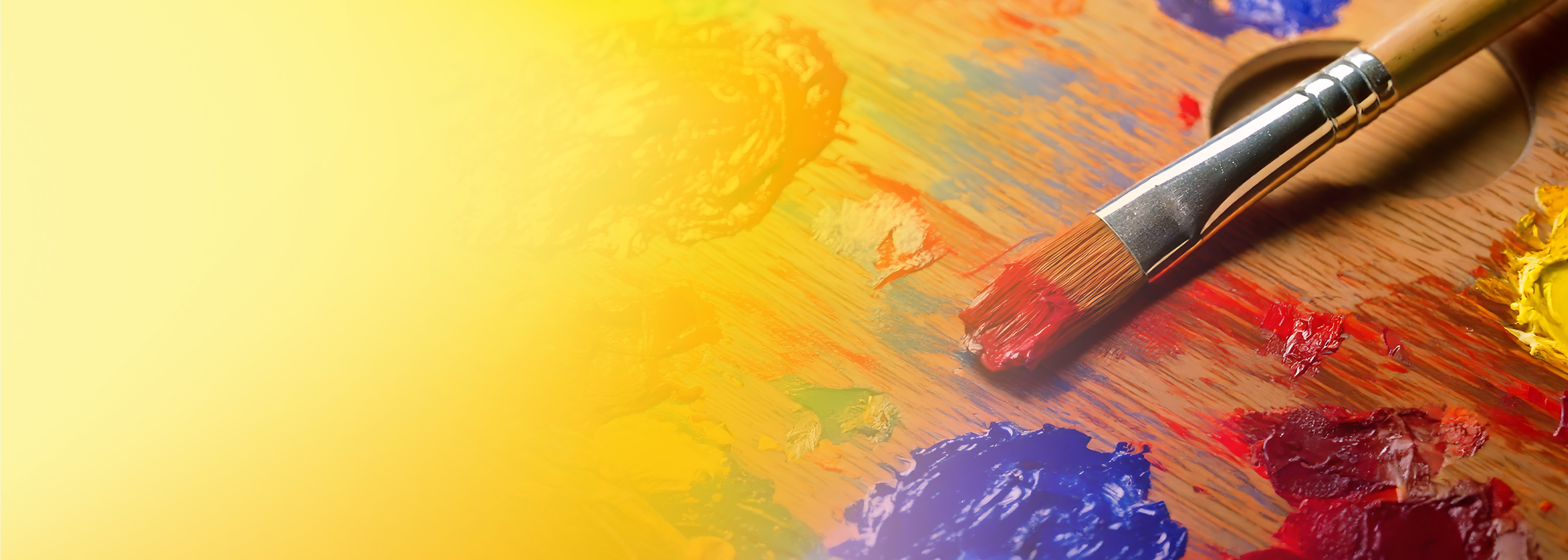 A close-up image of a paintbrush resting on a wooden palette with vivid blobs of paint in various colors and a yellow gradient background.