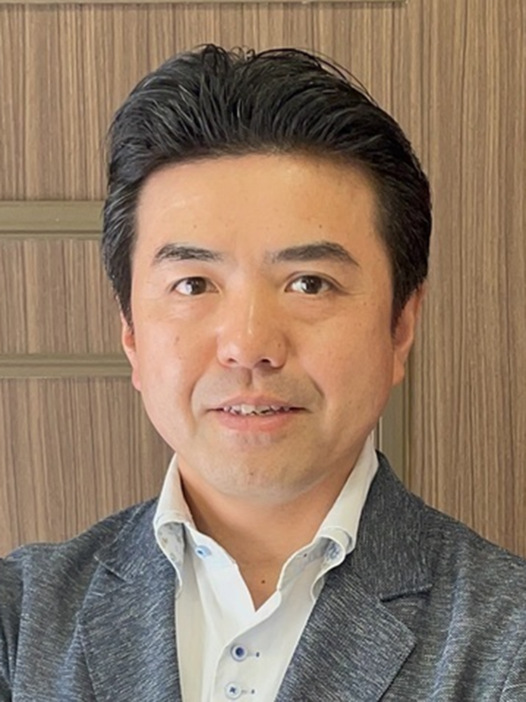 Portrait of an Asian man wearing business attire, standing in front of a wooden background.