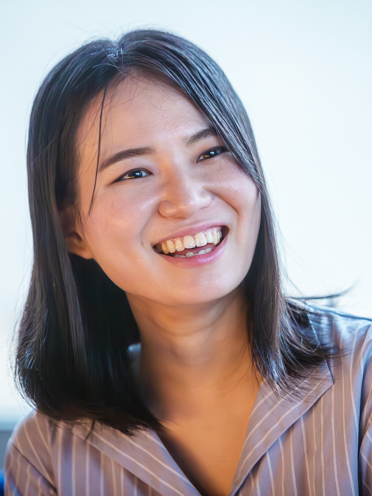 Closeup of a smiling woman wearing a casual striped shirt.