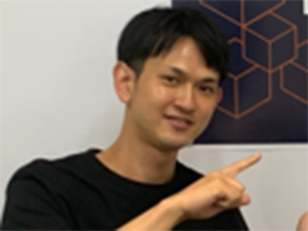 A man is pointing at a geometric poster on the wall.