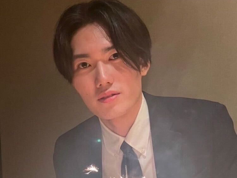 Portrait of a young man wearing a suit and tie, illuminated by candlelight.