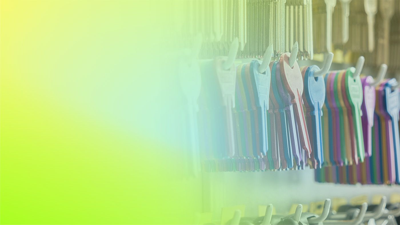 A row of colorful blank keys hanging on a rack, with a soft gradient background on the left side of the image.