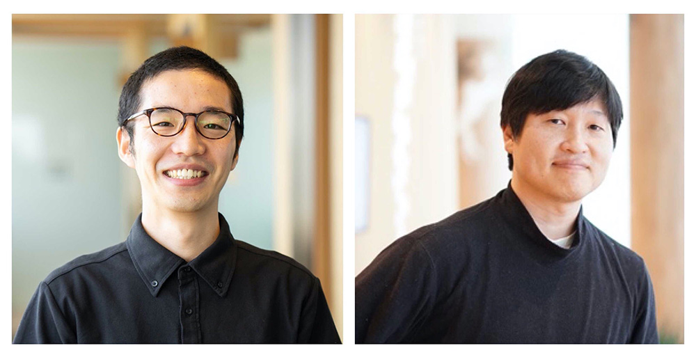 Two men indoors, both dressed in casual black attire, smiling and posing for a portrait in a bright setting.