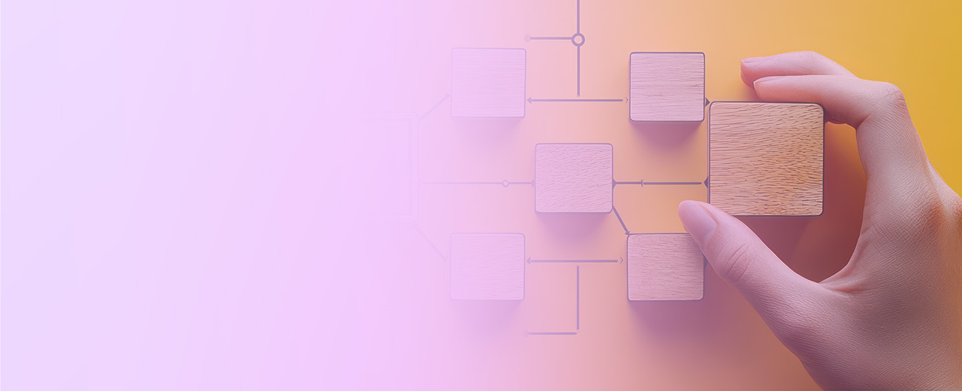 A hand is arranging wooden blocks to construct a flowchart or organizational diagram on a yellow and pink gradient background. The blocks are interconnected by lines, symbolizing structure or workflow.