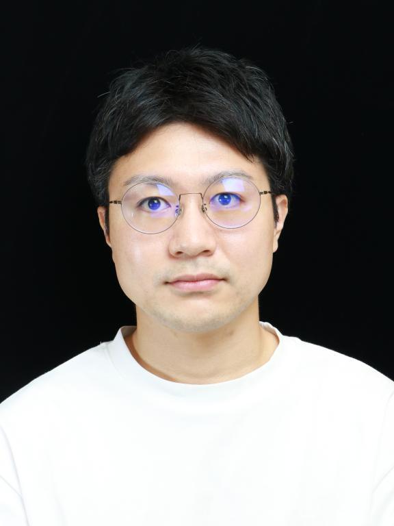 A portrait photograph of a person wearing a white shirt and glasses, set against a black background.