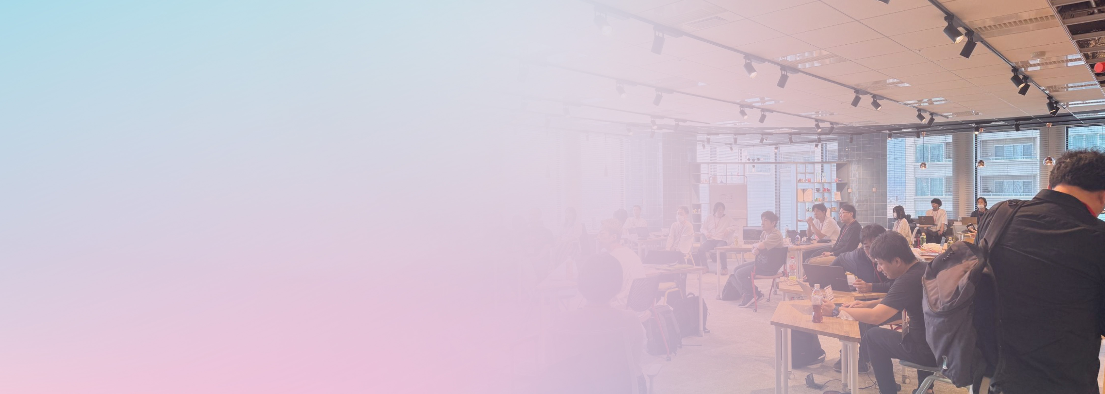 A photo of a developer community event or workshop, with people gathered and collaborating in a modern, well-lit room. The image features a pastel gradient overlay for a welcoming and creative atmosphere.