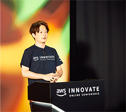 A speaker presenting at the AWS Innovate Online Conference, standing behind a podium with the AWS Innovate logo.