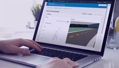 A person using a laptop displaying the AWS DeepRacer simulator with the Silverstone model evaluation track on the screen.