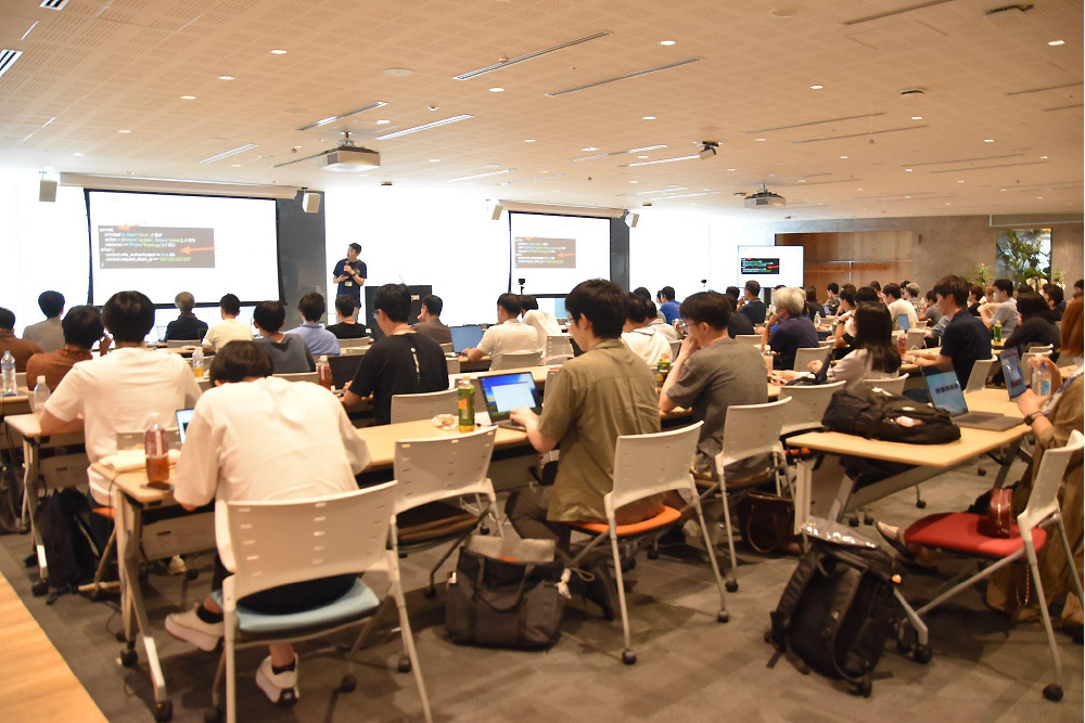 A speaker presents on security topics at JAWS DAYS 2023 tech conference, with a large audience attending and viewing slides in a conference room.