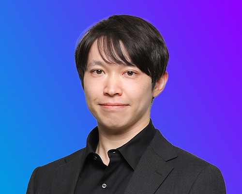 Portrait of a keynote speaker at AWS Summit Japan 2025, shown against a blue and purple gradient background, wearing a black shirt and dark blazer.