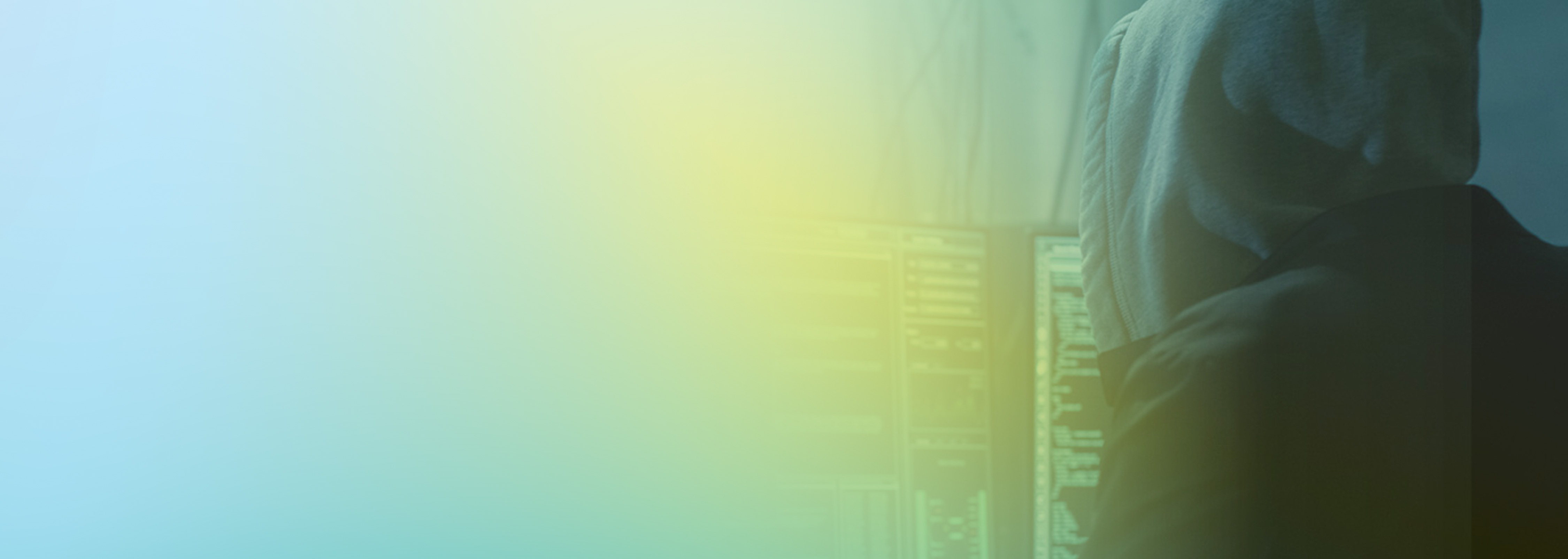 A person wearing a hood sits in front of multiple computer screens with code, symbolizing cybersecurity or hacking, with a blue and green gradient overlay.