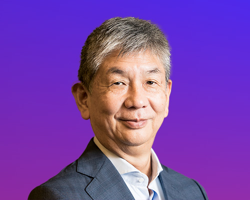 A professional portrait photograph of a man wearing a suit, set against a purple gradient background.