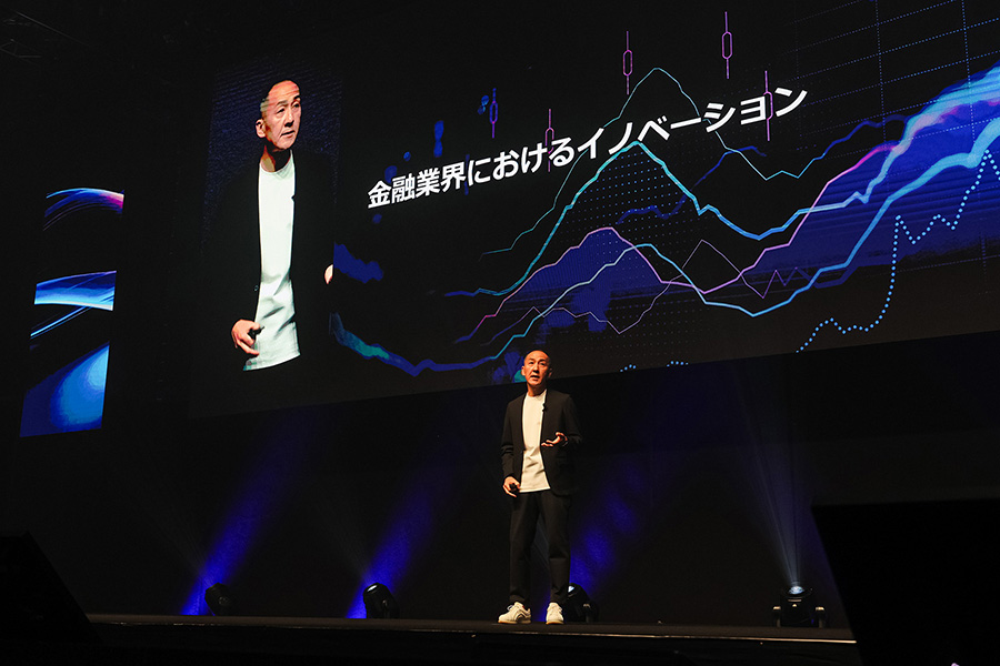 A speaker presents on stage at AWS Summit Tokyo 2025 in front of a large screen displaying a graph and Japanese text about innovation in the financial services industry.