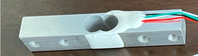 An aluminum load cell device with attached wires, used for measuring weight or force in IoT applications.
