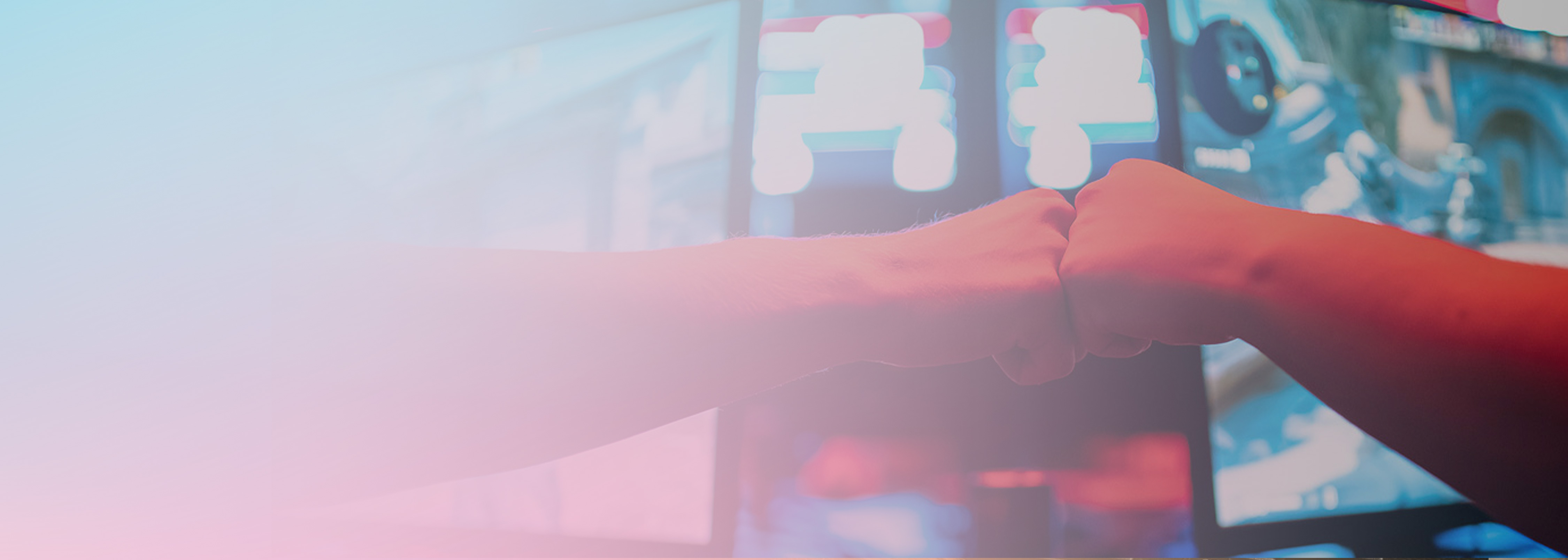 Two people fist bump in front of computer gaming screens with a soft pink and blue overlay, representing teamwork and collaboration, suitable for a DynamoDB serverless friend microservice context.