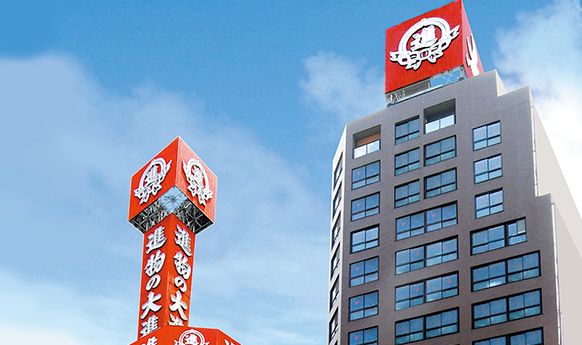 Exterior view of the Daishin Honten building with distinctive red signage, clear blue sky in the background.