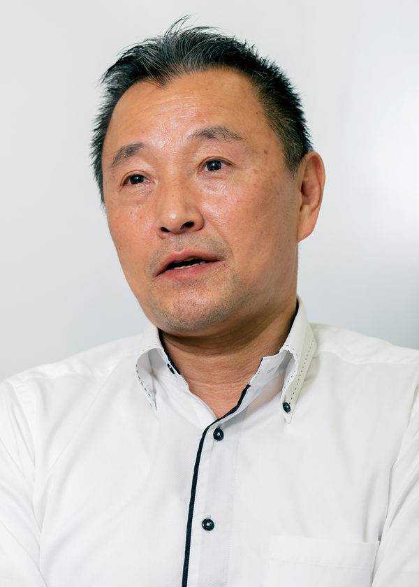 A person wearing a white collared shirt with black trim, set against a plain background.