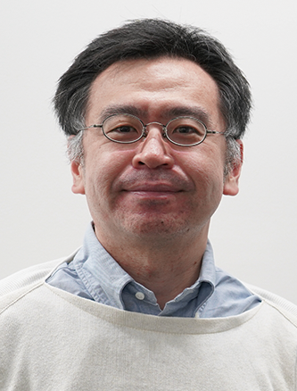 Portrait of a middle-aged man with glasses wearing a light sweater over a collared shirt, facing forward and smiling slightly.