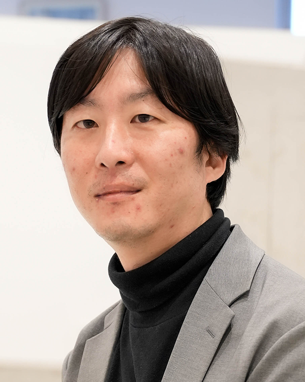 Portrait photo of a speaker featured in the Felissimo case study, wearing a gray blazer and black turtleneck, with a neutral background.
