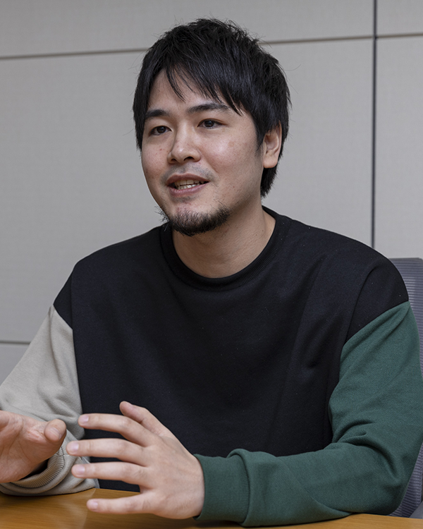 Saison Technology導入事例のインタビュー風景。テーブルの前で話している黒髪の男性。