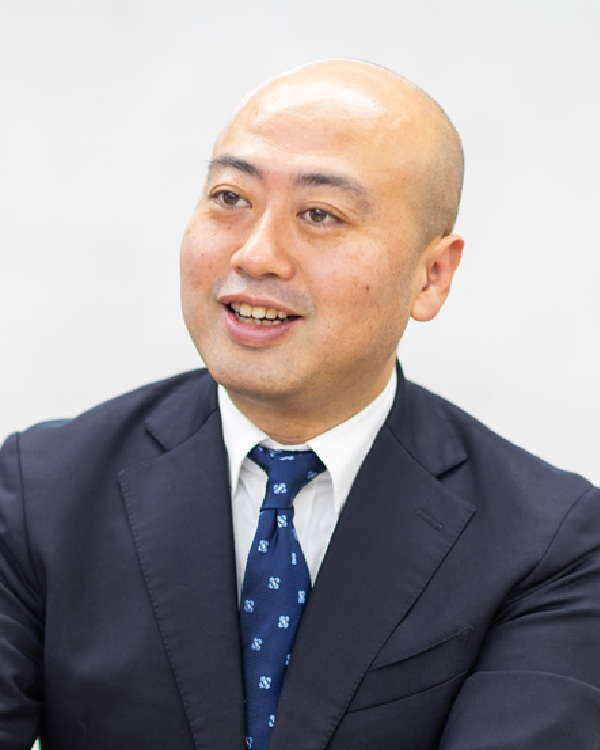 A professional portrait of a man in a suit, featured for the Yasashii-te case study by AWS Japan.