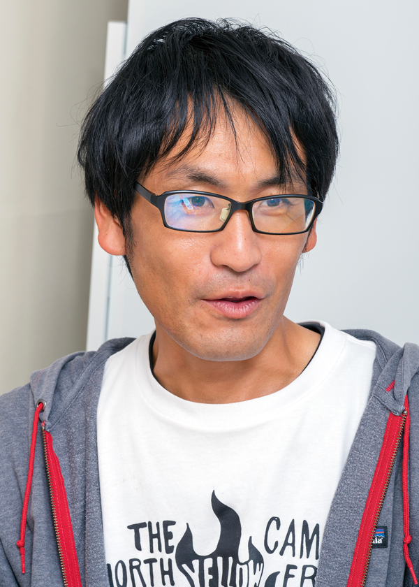 A person wearing a white graphic T-shirt with text and a flame design, layered with a gray hoodie featuring red drawstrings.