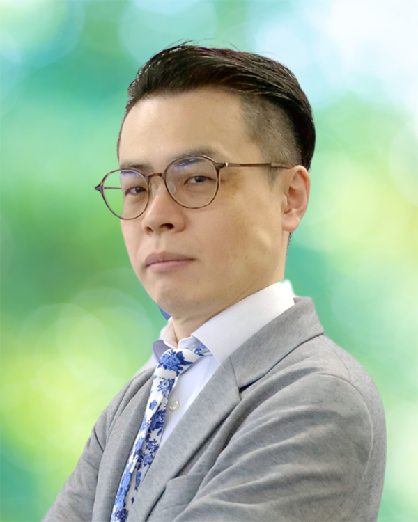 Portrait of a business professional wearing glasses, a suit, and a patterned tie, with a blurred green background. Used for the Machida Wada case study.
