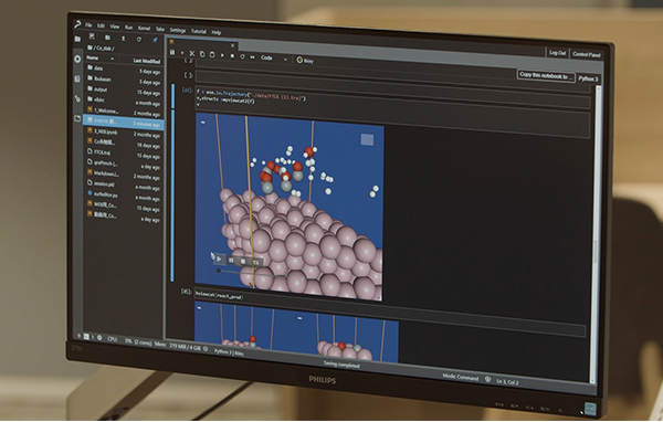 A computer monitor displays a computational chemistry visualization and code editor, showcasing molecular modeling or simulation software running on AWS infrastructure.