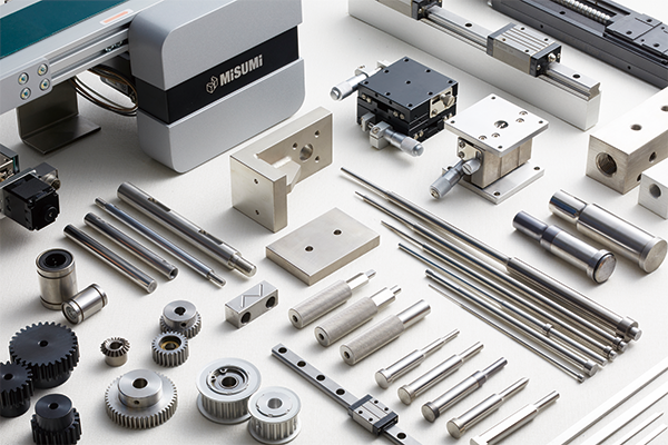 Alt-text: A collection of precision mechanical components, including gears, rods, plates, and linear motion systems, displayed on a white surface with a Misumi-branded machine in the background.