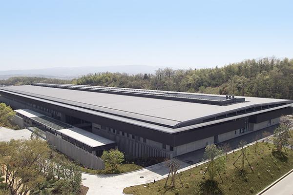Exterior view of Omron company building surrounded by trees and greenery.