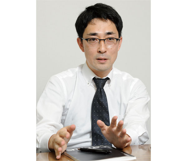 Person in business attire seated at a table during a Nikkiso case study interview, gesturing while speaking.