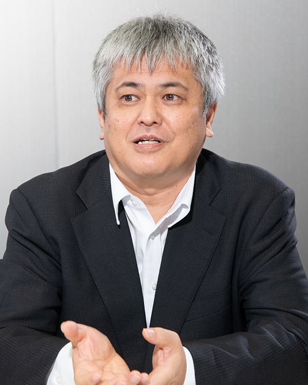 A portrait of a person in a business suit, featured in the Toshiba case study. The individual is seated against a neutral background.