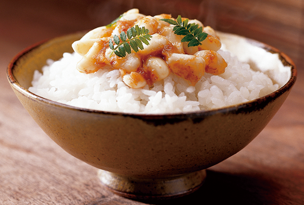 A bowl of cooked white rice topped with a savory sauce and garnished with green herbs, as featured in the Umeshin solution case study.